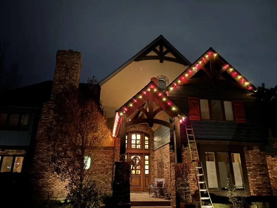 Craftsman entry with red and white bulbs along the timber gables